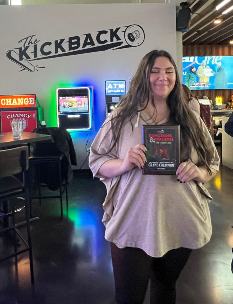 Mary holding up the D&D launch party grand champ plaque