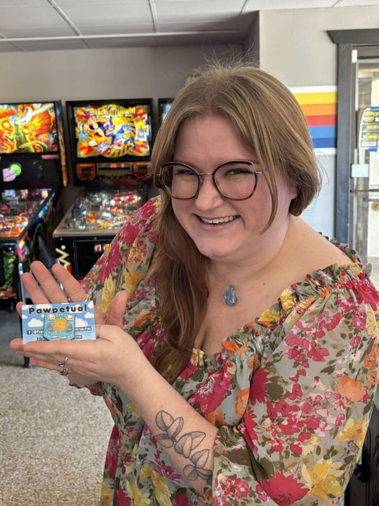 Belles holding an enamel pin prize