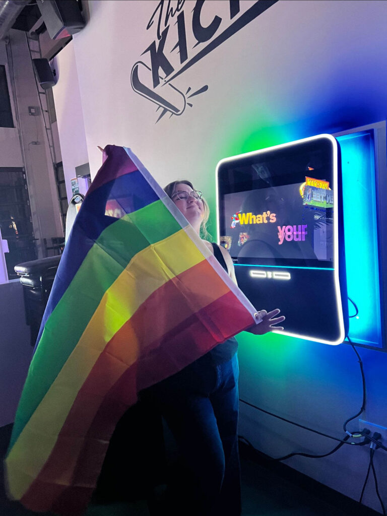 Amiee holding a pride flag and smiling