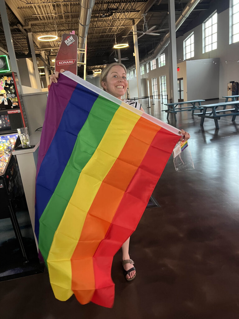 Lauren smiling and holding a pride flag
