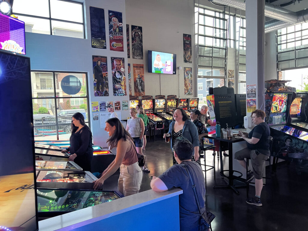 People laughing and playing pinball at The Kickback