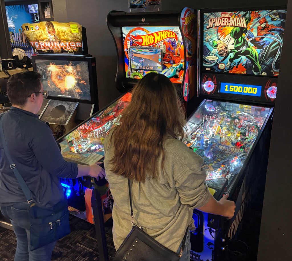 Two belles playing pinball at Doubletap