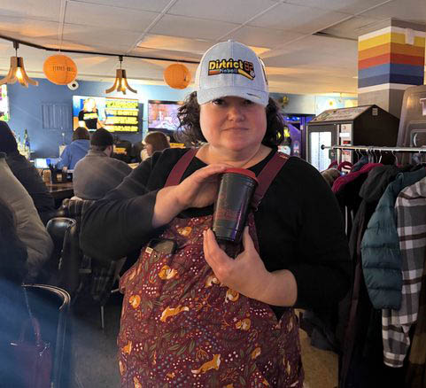 Tamara holding a cup and a District 82 hat