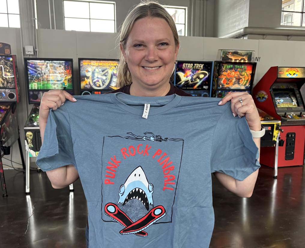 Donelle holding her winning punk rock pinball shark shirt