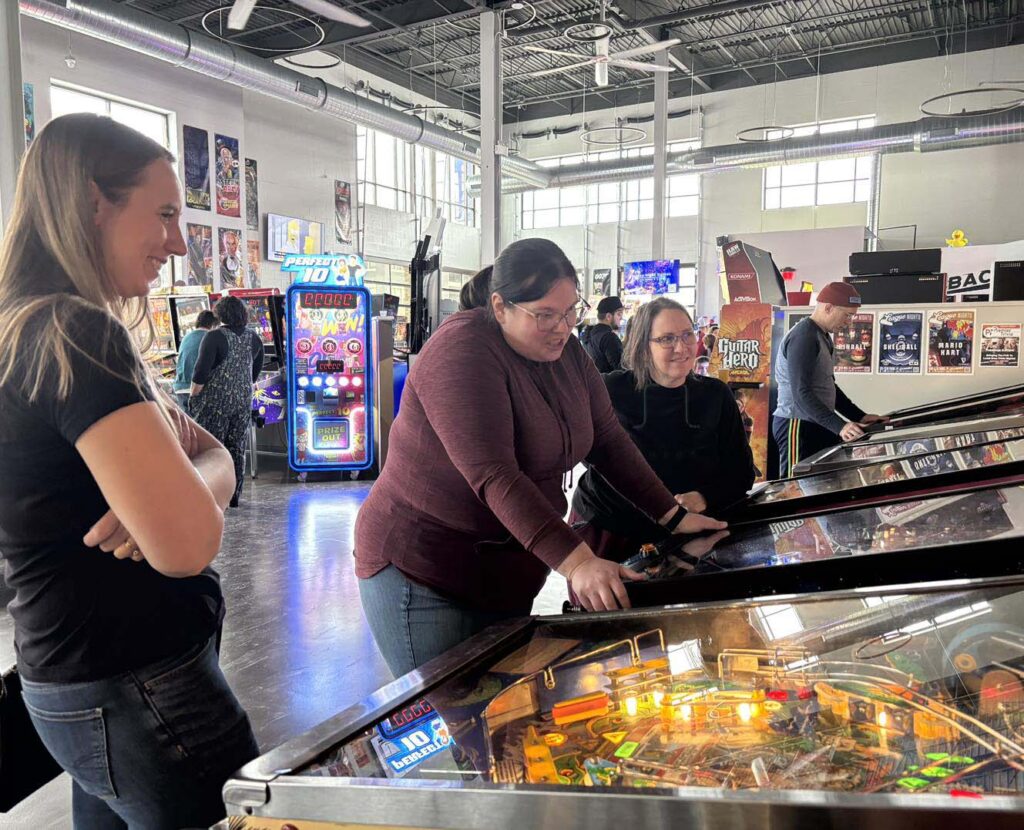 Belles playing pinball at The Kickback