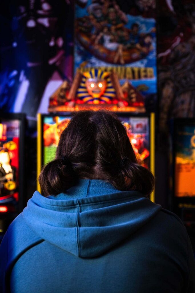 A woman playing Iron Maiden pinball