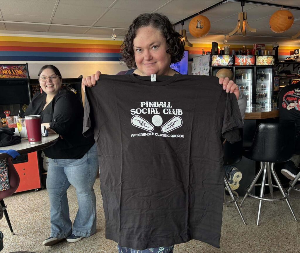 Holding a winningn Pinball Social Club shirt